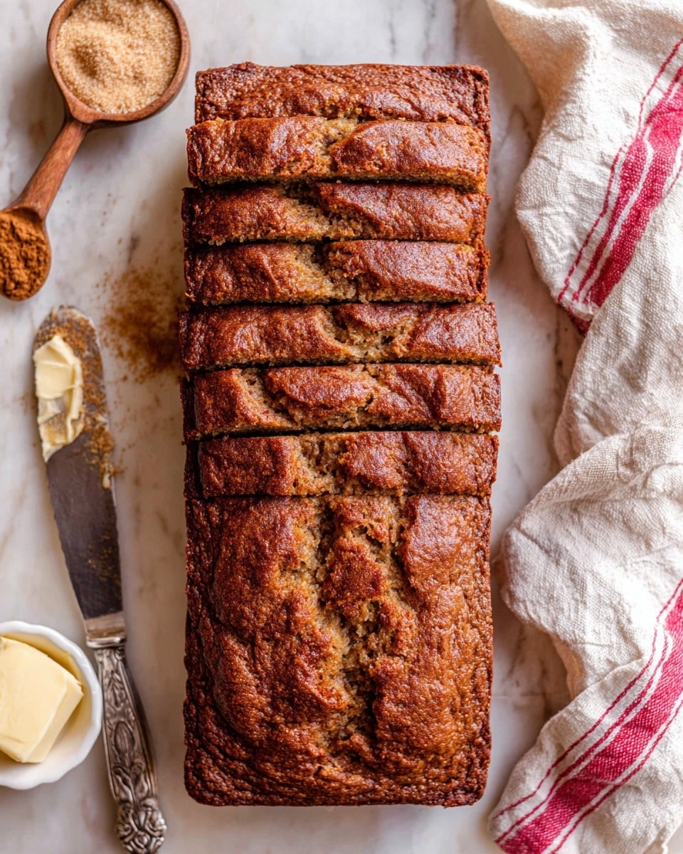 A loaf of banana bread with a dark brown, cracked top crust is shown sliced into 10 thick pieces and laid flat from top to bottom on a white marbled surface. To the left, there is a silver knife with a dollop of butter on its blade, resting beside a small white bowl filled with light brown sugar. Above the bowl, a small wooden spoon with cinnamon powder lies partially visible. On the right side, a white cloth with red stripes is loosely folded next to the loaf. Photo taken with an iphone --ar 4:5 --v 7