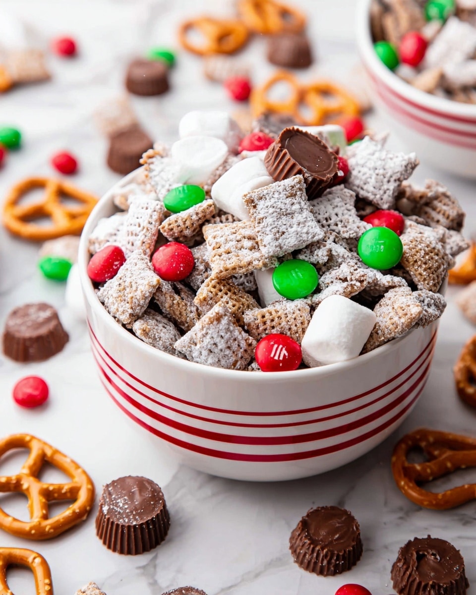 The image shows a white bowl with red stripes filled with a festive snack mix. The mix contains several layers and types of snacks: the base layer is square cereal pieces dusted with white powdered sugar giving a rough, powdery texture; mixed throughout are small soft white marshmallows, smooth round red and green candy-coated chocolates, and light brown pretzels with a glossy finish. On top, there are several chocolate peanut butter cups with a ridged edge and smooth top. Scattered outside the bowl on a white marbled surface are more of the same ingredients, with extra chocolate peanut butter cups and pretzels visible nearby. Photo taken with an iphone --ar 4:5 --v 7