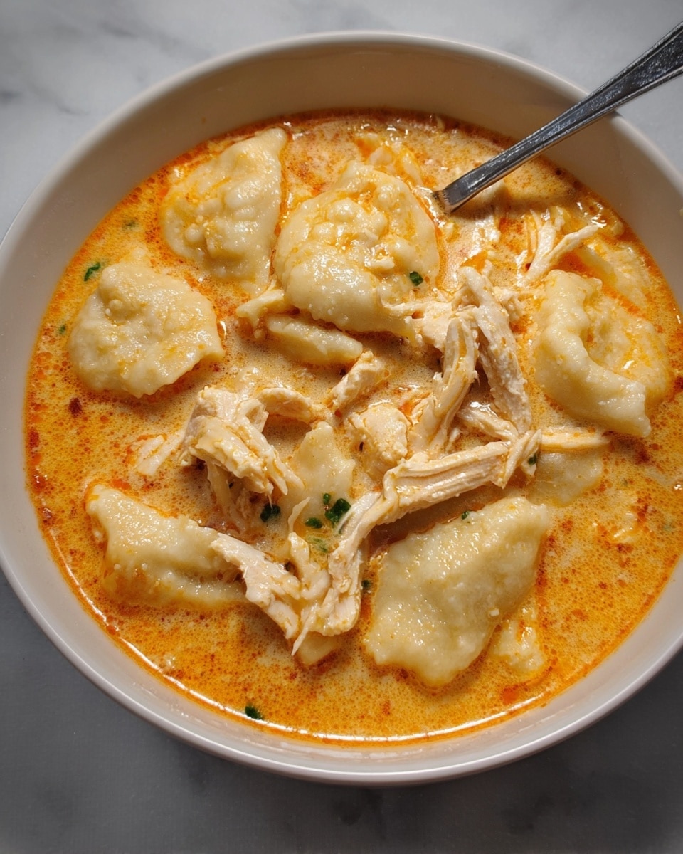 A close-up of a spoon holding two scoops of food above a white bowl filled with the same dish. The first scoop is pale yellow with a soft, fluffy texture and small bits of green herbs and corn. The second scoop is light beige with soft, shredded chicken pieces layered inside. The bowl underneath is filled with more of the same layered food, blending soft yellow and light beige colors. The background shows a white marbled surface with a colorful, striped cloth blurred behind the bowl. Photo taken with an iphone --ar 4:5 --v 7