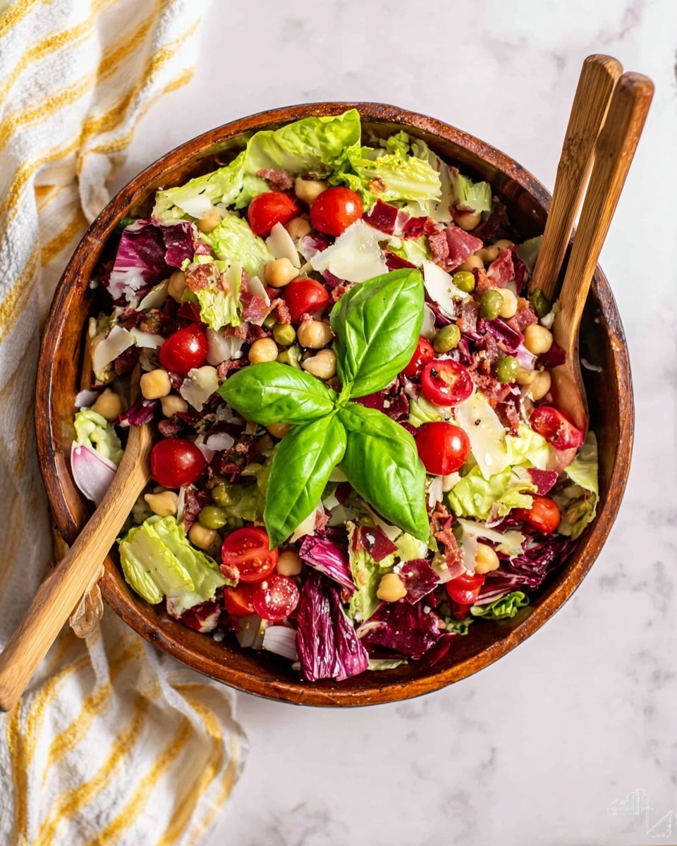 A large brown bowl filled with a mixed salad sits on a white marbled surface, with two wooden salad spoons resting inside. The salad has many layers and colors: light green lettuce leaves, dark red radicchio, bright red cherry tomato halves, pale chickpeas, thin slices of pale yellow cheese, purple onion pieces, green capers, and small chunks of reddish cured meat. Fresh green basil leaves are placed on top in the center. A white cloth with light yellow and gray stripes is partially visible in the background. photo taken with an iphone --ar 4:5 --v 7