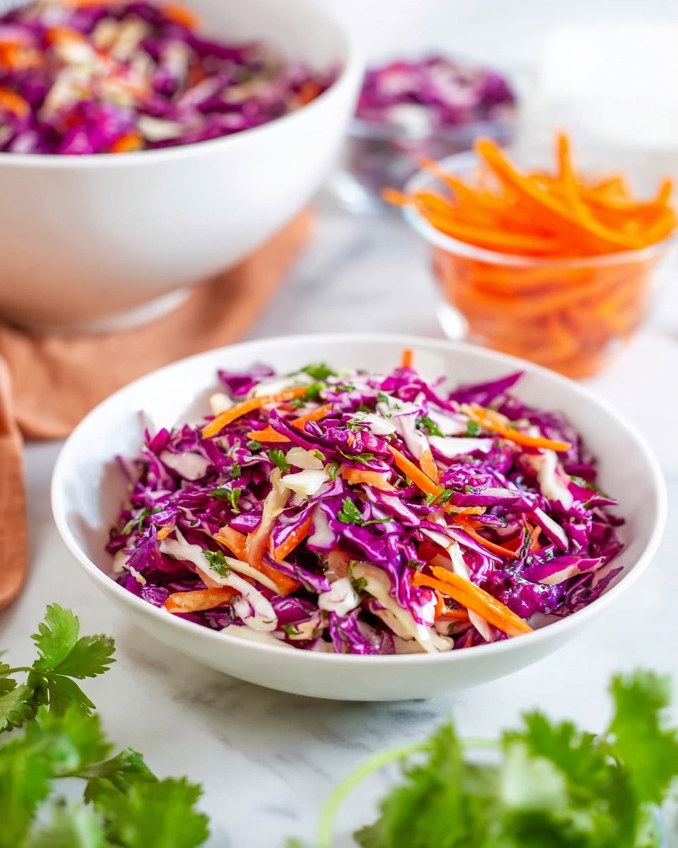 A close-up of a white shallow bowl filled with a colorful cole slaw made of bright purple cabbage shredded into thin pieces, mixed with thin orange carrot strips and small pieces of white onion, all tossed with chopped green herbs visible throughout. In the background, a larger white bowl holds more of the same salad, while fresh carrot strips are in a small clear bowl nearby. The setting is on a white marbled surface with fresh cilantro leaves spread around, giving a fresh and vibrant feel. Photo taken with an iphone --ar 4:5 --v 7