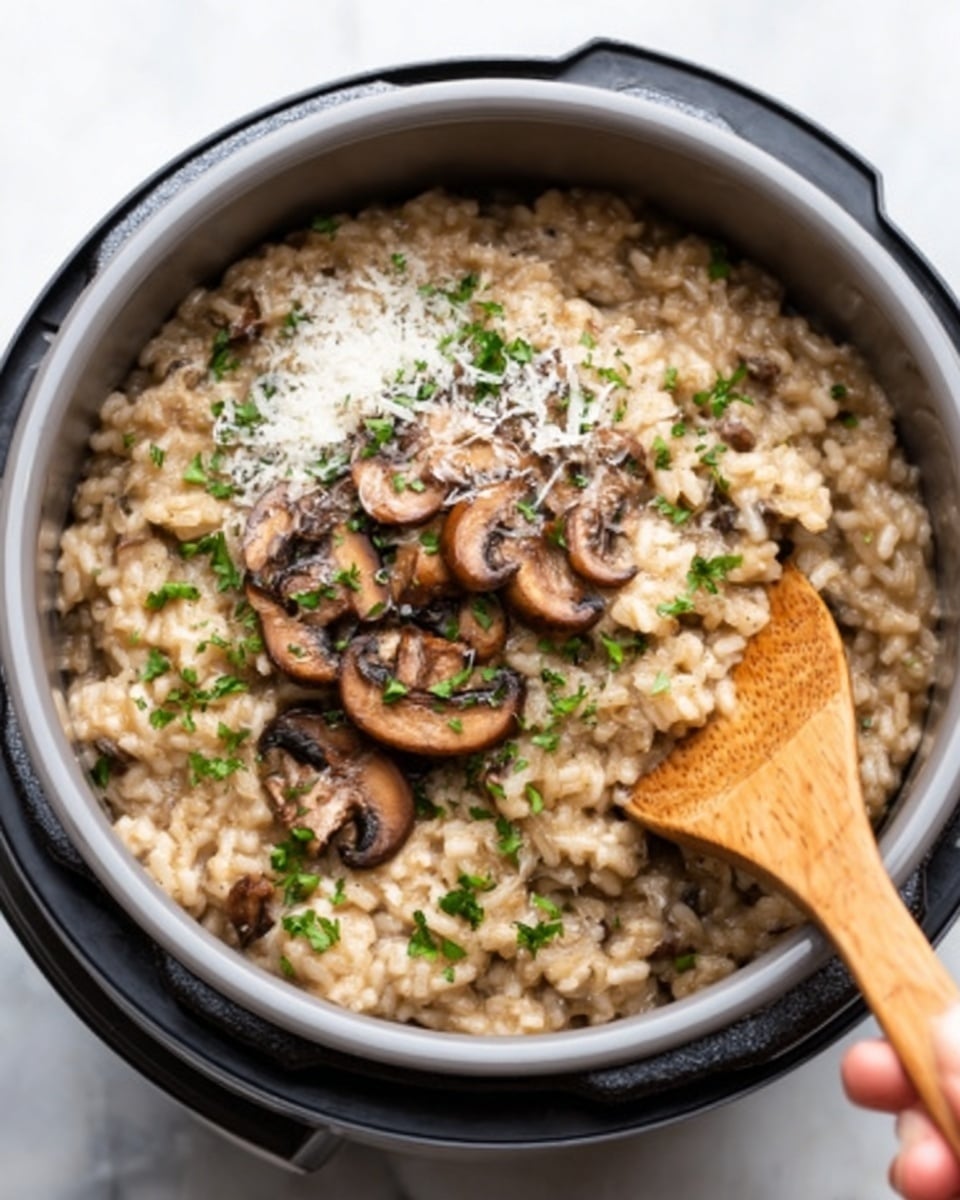 The image shows a gray pot filled with creamy mushroom risotto. The risotto has a light brown color mixed with small pieces of cooked mushrooms throughout. On top, there are several sliced, browned mushrooms arranged neatly in the center, garnished with chopped green herbs and a sprinkle of white grated cheese. A wooden spoon with a woman's hand holding it is dipping into the risotto from the right side. The pot is placed on a white marbled surface, giving a clean and fresh look. Photo taken with an iphone --ar 4:5 --v 7