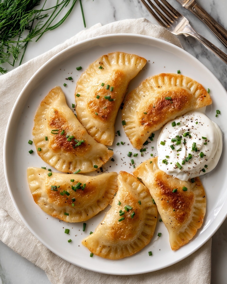 A white plate holds seven golden-brown potato pierogi arranged in a loose circle. Each pierogi is half-moon shaped with a bubbly, crispy texture on top and slightly crimped edges. They are sprinkled with small bits of green chives and a dusting of black pepper. In the center-right of the plate, there is a generous dollop of white sour cream, also topped with chopped chives and black pepper. The plate sits on a white marbled surface with a folded light gray cloth underneath, and a silver fork is visible in the upper right corner. A sprig of green leafy herb is placed next to the plate for decoration. Photo taken with an iphone --ar 4:5 --v 7