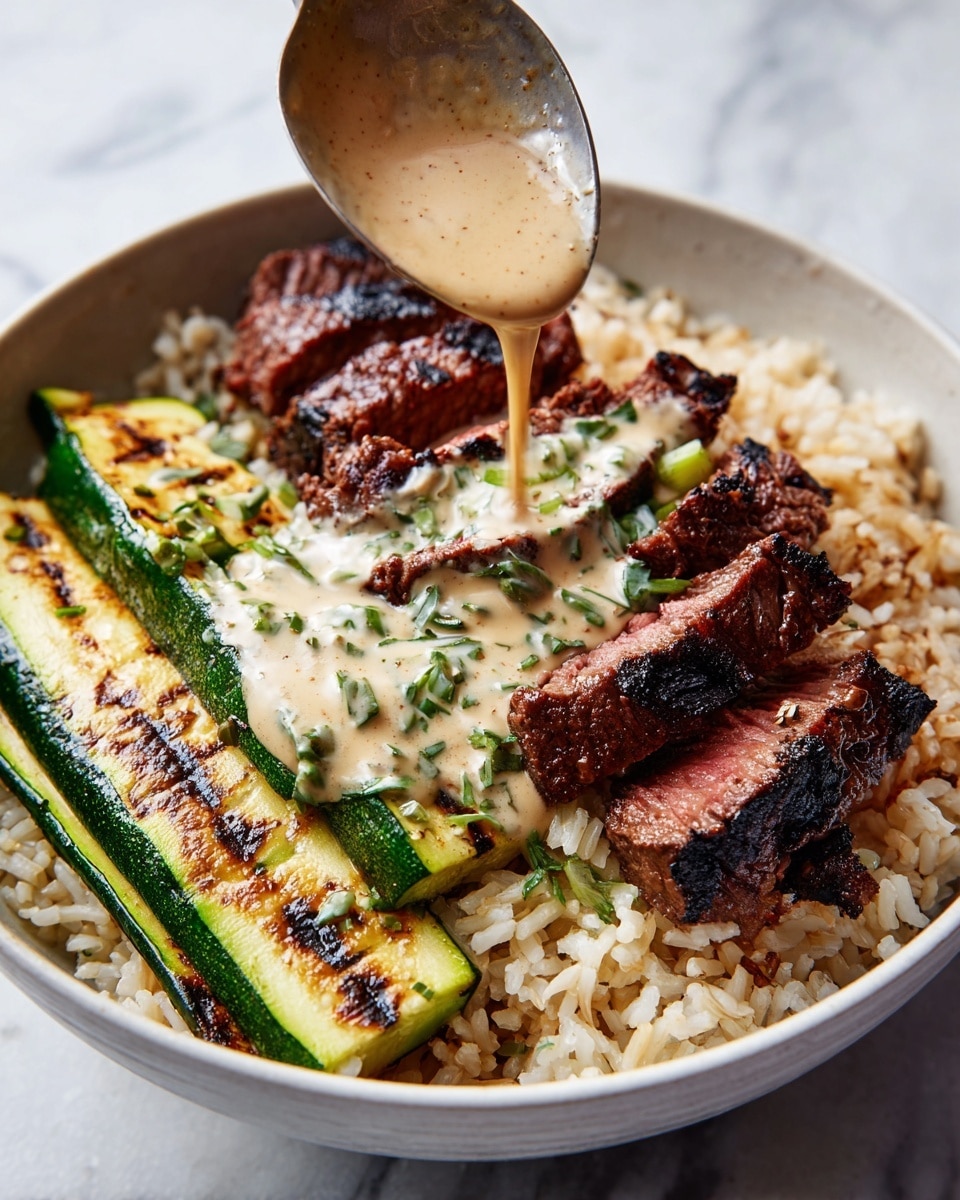 A gray bowl sits on a white marbled surface, filled with three main layers. On the left, there are slices of grilled steak with a dark, charred outer layer and pinkish, juicy centers, arranged neatly. To the right, there are long strips of grilled zucchini with dark grill marks and green edges. In the background, underneath the steak and sauce, there is a layer of brown rice mixed with green herbs. A creamy, light beige sauce with green herb pieces is being poured over the steak and cutting into the rice, adding a smooth texture on top. Steam rises from the bowl, showing it is hot. Photo taken with an iphone --ar 4:5 --v 7