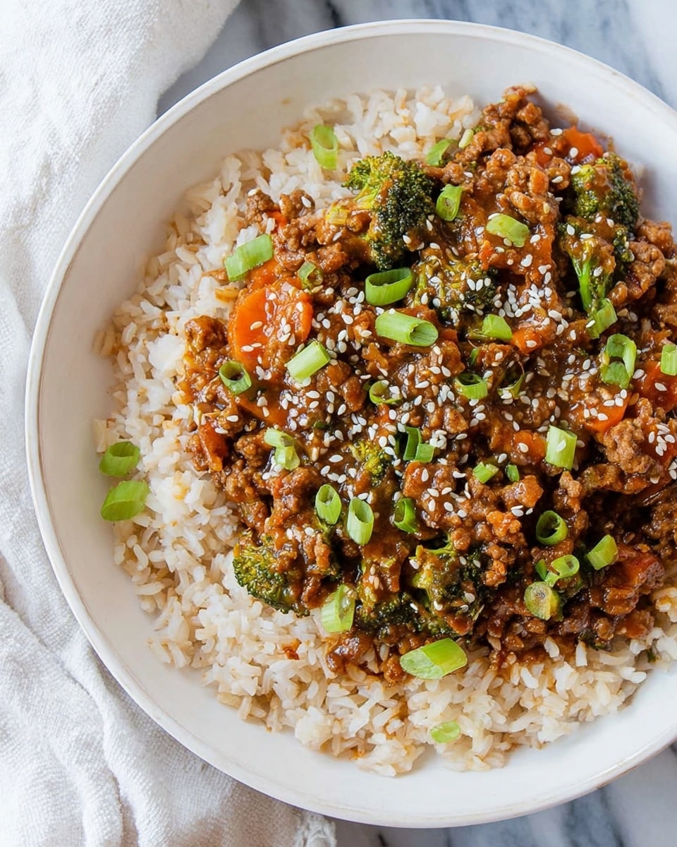 A white bowl filled with two layers: the bottom layer is fluffy light brown rice, and the top layer is a mix of cooked ground meat with small pieces of bright orange carrots and green broccoli florets, all covered in a glossy brown sauce. The dish is sprinkled with white sesame seeds and chopped green onions, making the colors pop against the rice. The bowl sits on a white marbled surface with a white cloth to the side. photo taken with an iphone --ar 4:5 --v 7