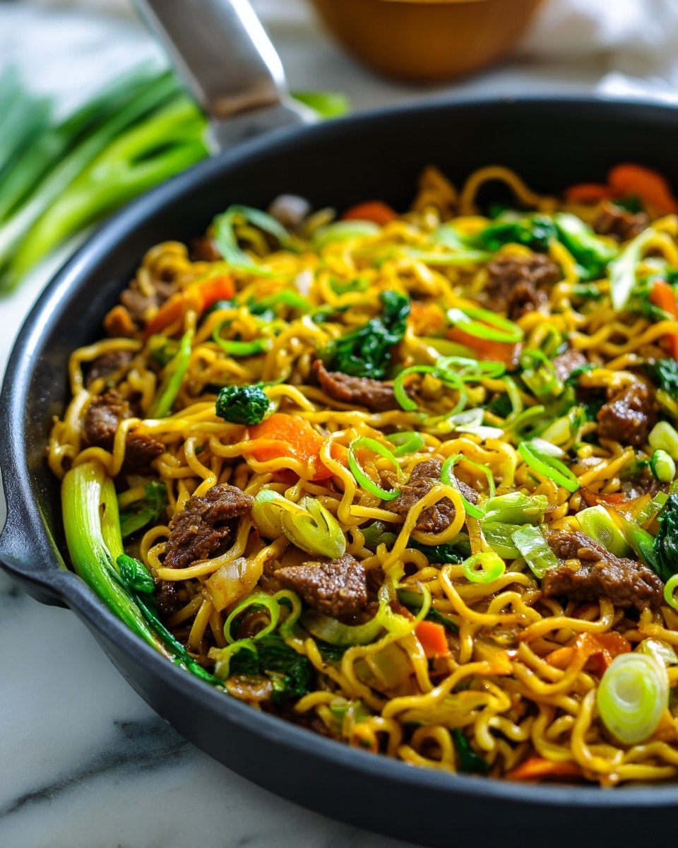 A close-up image of a black pan filled with a serving of noodles mixed with ground beef pieces spread evenly on top and throughout. The noodles are golden yellow, looking soft and slightly glossy, with small bits of chopped green onions sprinkled across them. Bright green vegetable leaves and thin orange carrot strips are layered on one side, adding color contrast. The pan sits on a white marbled surface with a blurred warm background. Photo taken with an iphone --ar 4:5 --v 7