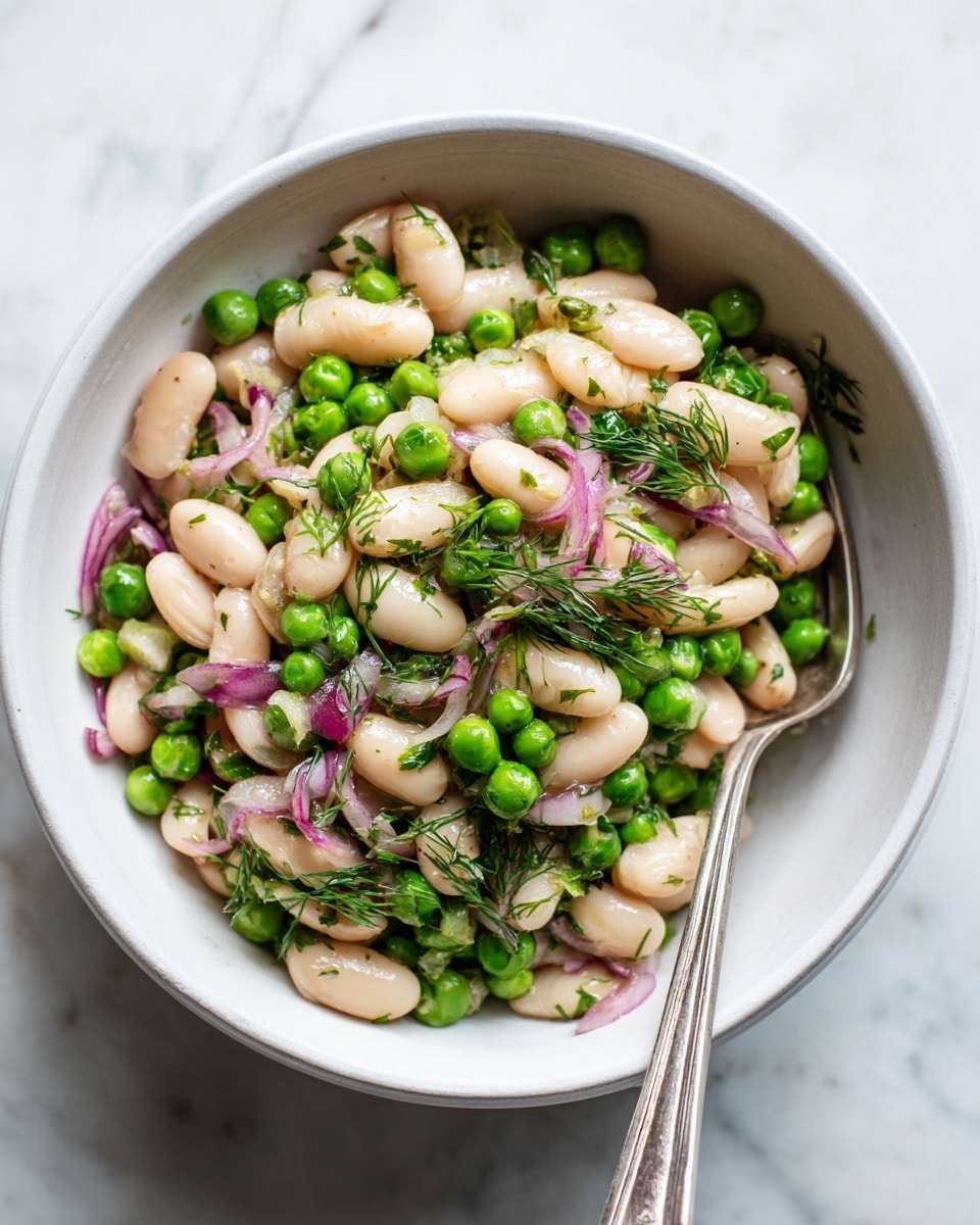 A close-up of a white bowl filled with a fresh salad made of white beans and green peas mixed with chopped dill and small pieces of red onion. The beans are plump and soft-looking, pale cream in color, while the peas are bright green and round. The herbs are finely chopped and evenly spread on top, adding a touch of texture and freshness. A silver fork rests inside the bowl on the right side, partly buried in the salad. The background is a white marbled texture. photo taken with an iphone --ar 4:5 --v 7