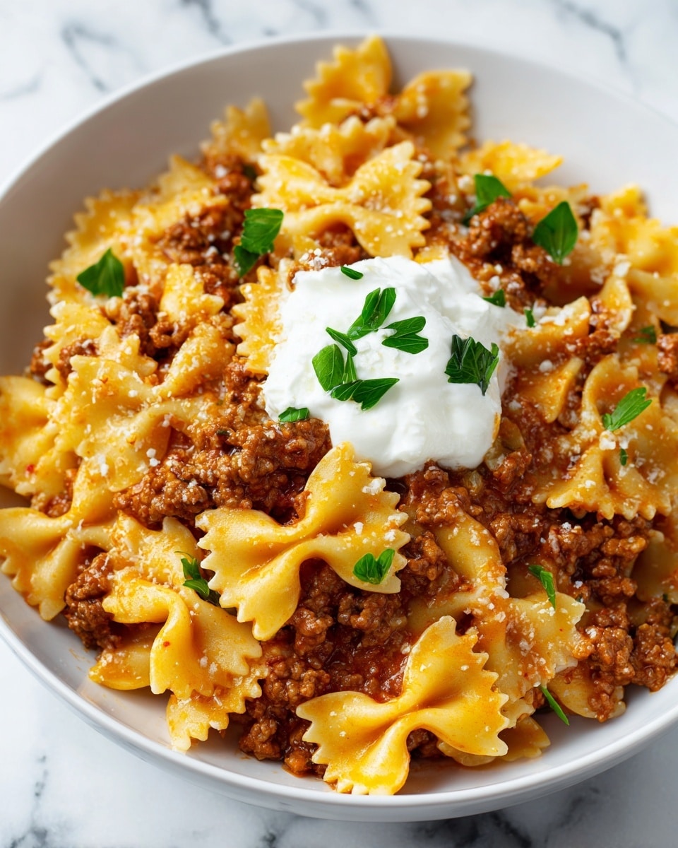 A white bowl holds a layered pasta dish with farfalle pasta on top, light orange in color and smooth in texture. Beneath the pasta is a layer of ground meat sauce, brown and crumbly, mixed with small green parsley leaves scattered across the dish. In the center, there is a dollop of white sour cream, slightly soft and creamy, with more parsley garnish on top. The bowl sits on a white marbled surface, and a woman's hand is gently touching the bowl. Photo taken with an iphone --ar 4:5 --v 7