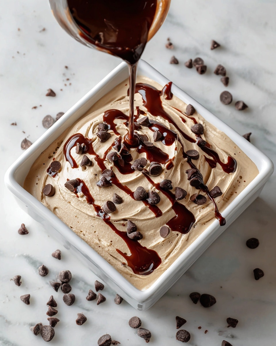 The image shows a square white dish filled with a creamy dessert topped with multiple round dollops of light brown whipped cream arranged in rows. Each dollop is sprinkled with small dark chocolate chips, and smooth, rich chocolate sauce is being poured over the top, creating a glossy layer that drips down between the dollops. Some scattered chocolate chips rest on a white marbled surface around the dish. The creamy texture of the dollops contrasts with the shiny drizzle of chocolate sauce and the small, crunchy chips. Photo taken with an iphone --ar 4:5 --v 7