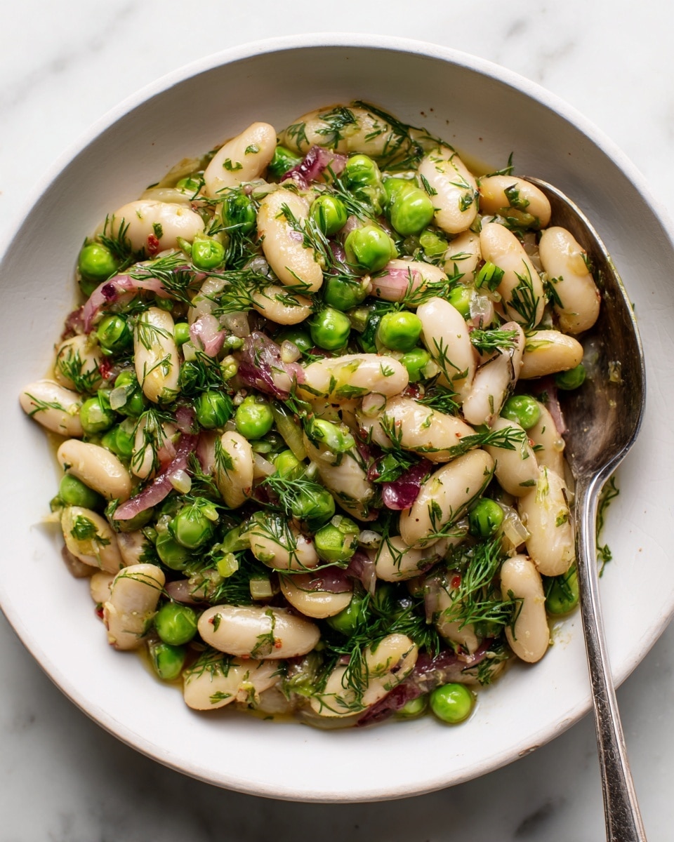 A white bowl filled with a salad made of white beans and bright green peas, mixed with small pieces of red onion and fresh green herbs, likely dill, all coated in a light dressing that makes the beans and peas shiny. A silver fork rests inside the bowl on the right side. The toppings create a mix of smooth, round white beans, small green peas, and finely chopped herbs on top, set on a white marbled surface. Photo taken with an iphone --ar 4:5 --v 7