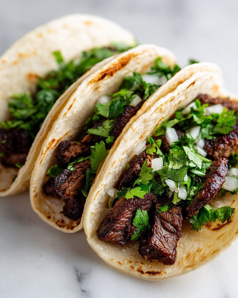 Three soft tacos are placed side by side on a white plate, each filled with small chunks of cooked beef that have a slightly crispy texture and deep brown color. On top of the beef, there is a layer of chopped fresh white onions and vibrant green cilantro leaves, adding a fresh look. The tortillas are light beige with some slight browning from frying, and the edges gently curl around the filling. The plate rests on a white marbled surface, creating a clean and bright setting. photo taken with an iphone --ar 4:5 --v 7